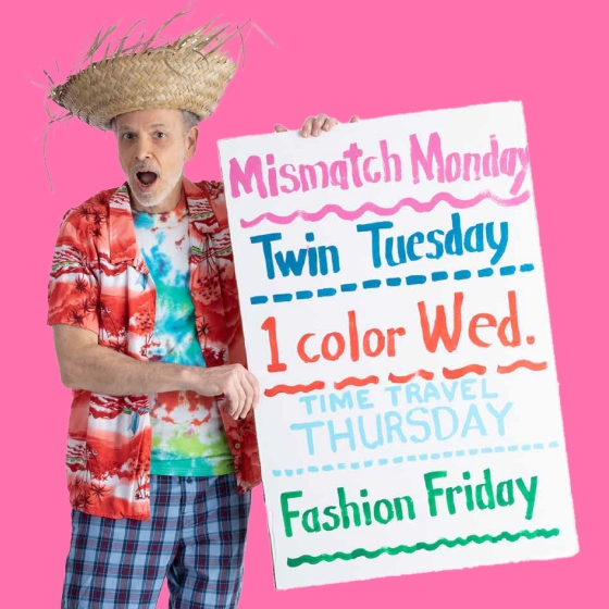 A man in a straw hat and Hawaiian shirt holds a sign reading "Mismatch Monday, Twin Tuesday, 1 color Wed, Time Travel Thursday, Fashion Friday"