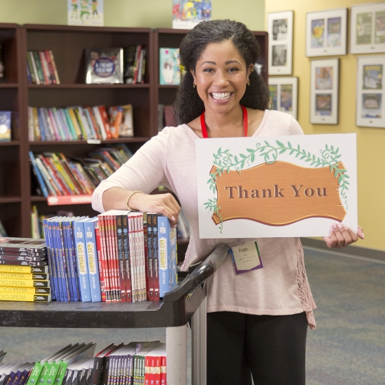 A teacher holds up a sign reading "Thank you"