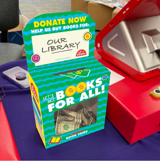 An All For Books change donation box with some dollar bills inside sits next to a Payment System register. The box says "Donate now, help us buy books for our library" 