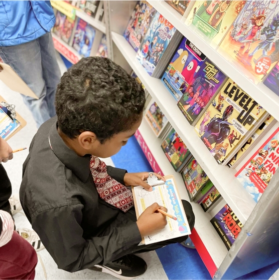 A student fills out his wishlist in front of a Book Fairs case full of books