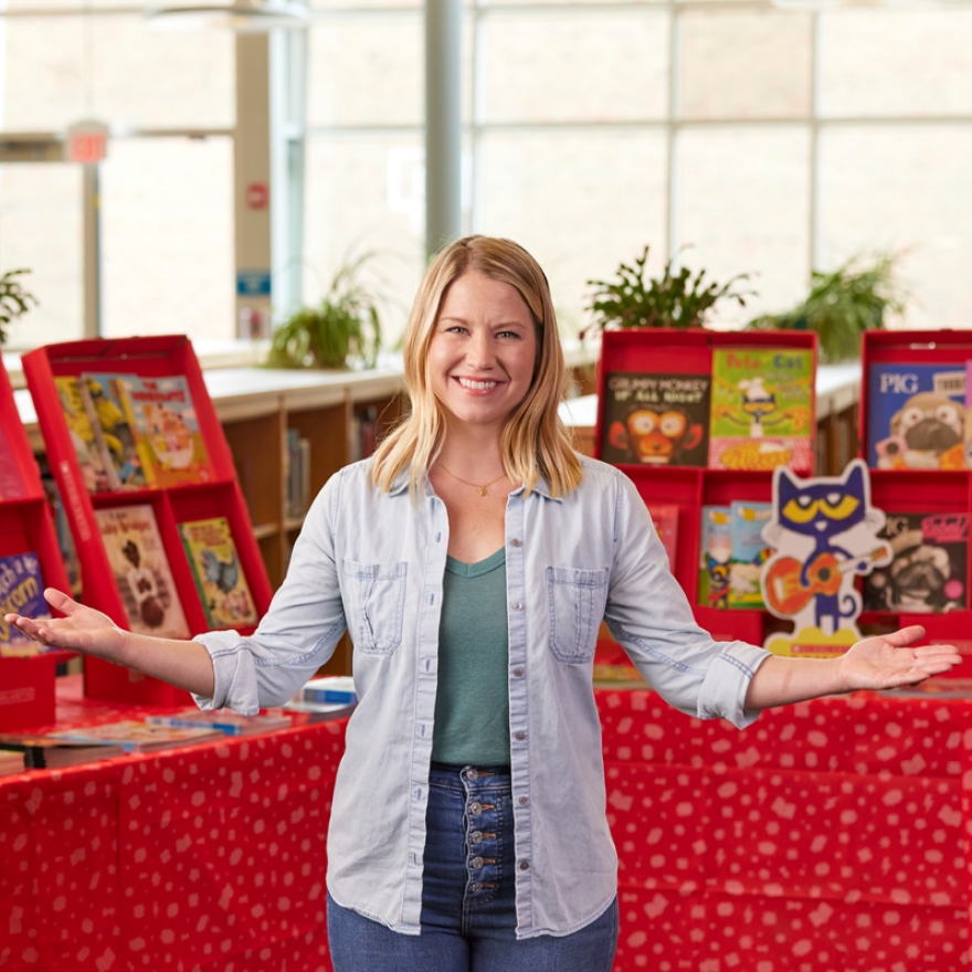A Host smiles widely while showcasing a Fair fully set up behind them