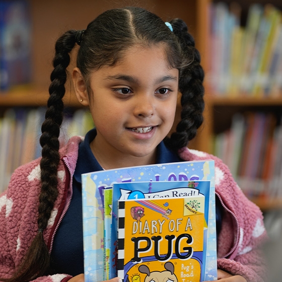 A student smiles with a stack of Book Fair books